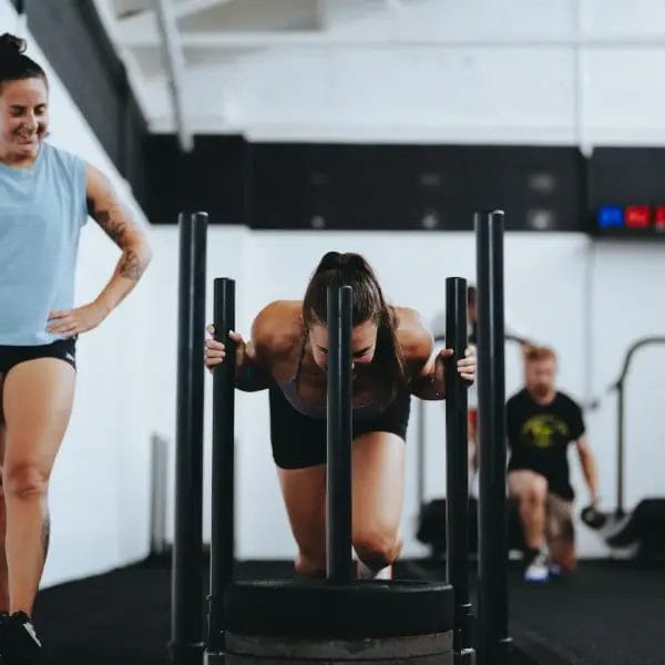 Young woman pushing sled on the training